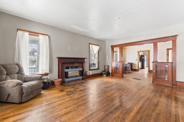 living room featuring hardwood / wood-style flooring, a fireplace, and decorative columns