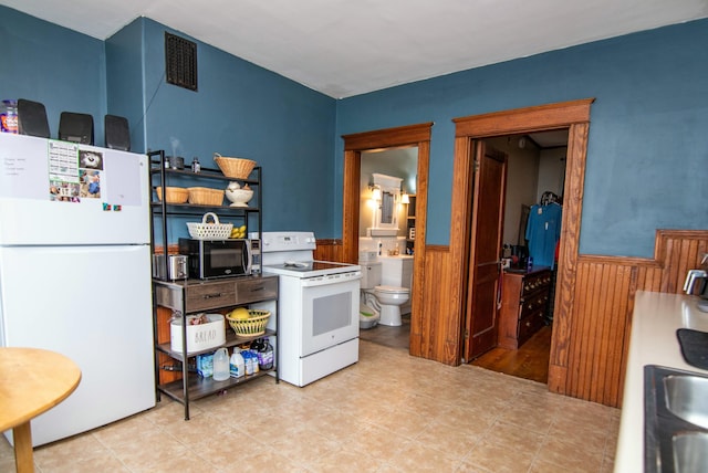 kitchen featuring sink, white appliances, and wooden walls