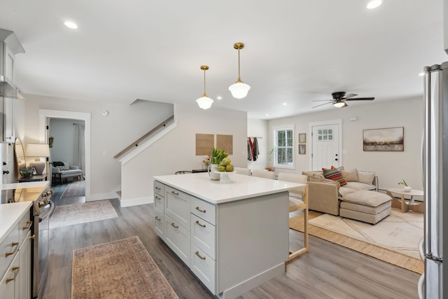 kitchen with hanging light fixtures, stainless steel appliances, hardwood / wood-style floors, and white cabinets