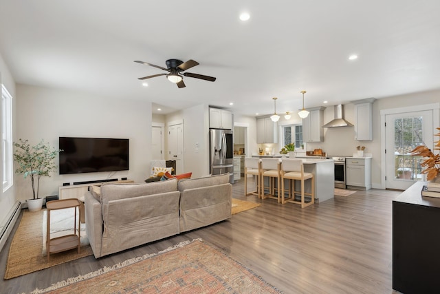 living room with baseboard heating, ceiling fan, and light hardwood / wood-style floors