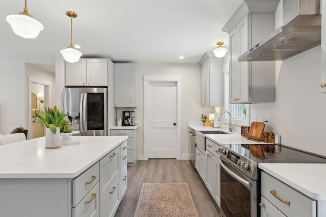 kitchen with decorative light fixtures, a center island, wall chimney range hood, stainless steel appliances, and white cabinets