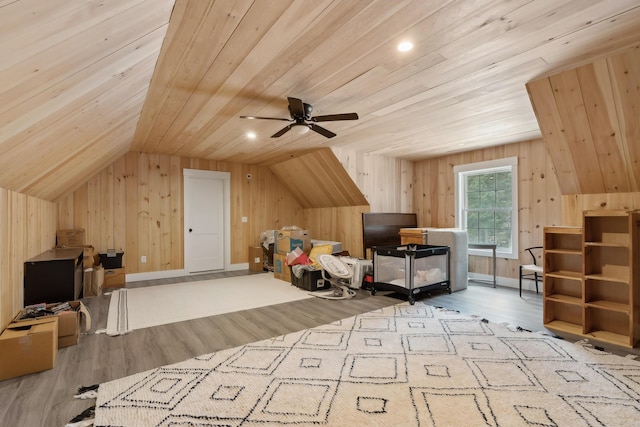 bonus room featuring vaulted ceiling, wooden ceiling, wooden walls, and light wood-type flooring