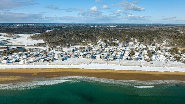 snowy aerial view with a water view and a view of the beach