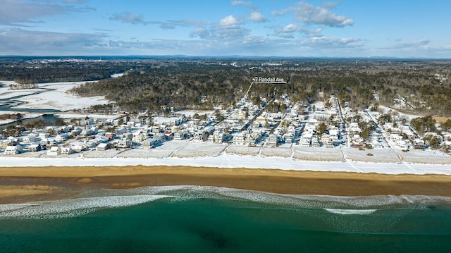 snowy aerial view with a water view and a beach view