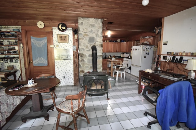 dining room featuring light tile patterned floors, wood ceiling, and a wood stove