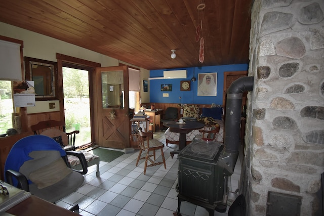 living room with light tile patterned flooring, a wood stove, wooden ceiling, and a wall unit AC