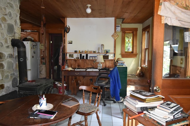 interior space featuring wood ceiling, light tile patterned floors, and a wood stove