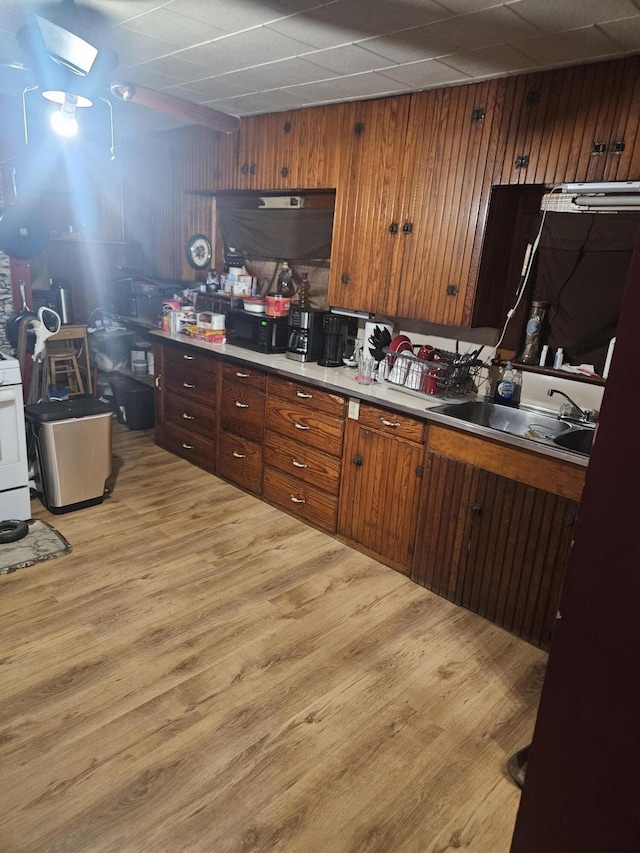 kitchen with range, wooden walls, sink, and light wood-type flooring