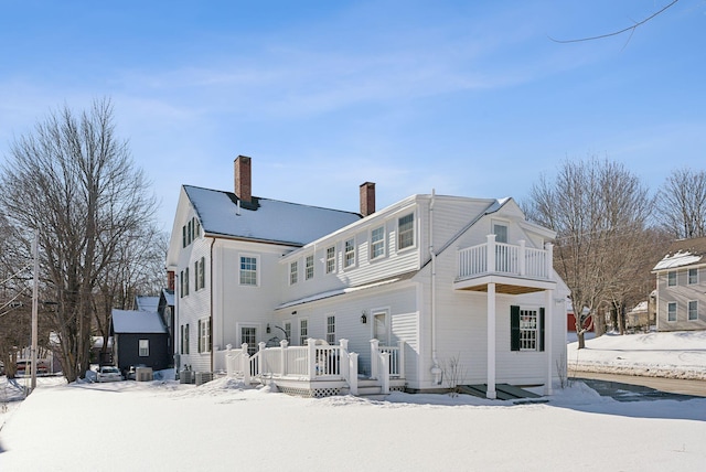 snow covered property with a wooden deck and a balcony