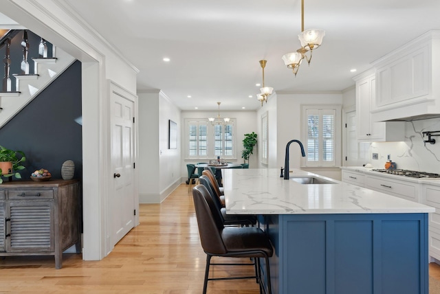 kitchen featuring hanging light fixtures, an island with sink, sink, and a notable chandelier