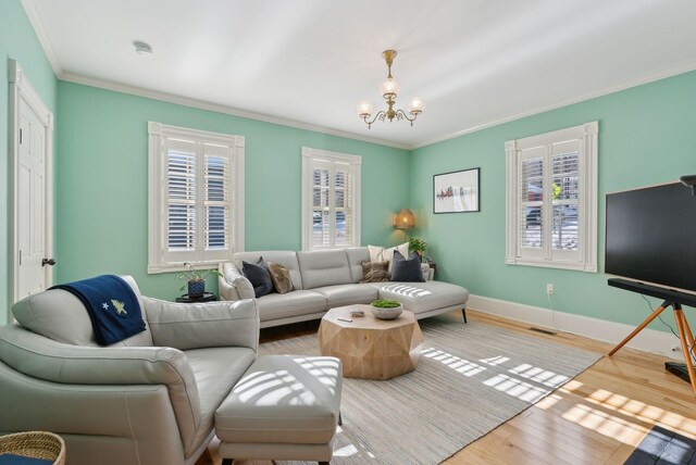 living room featuring an inviting chandelier, hardwood / wood-style floors, and crown molding