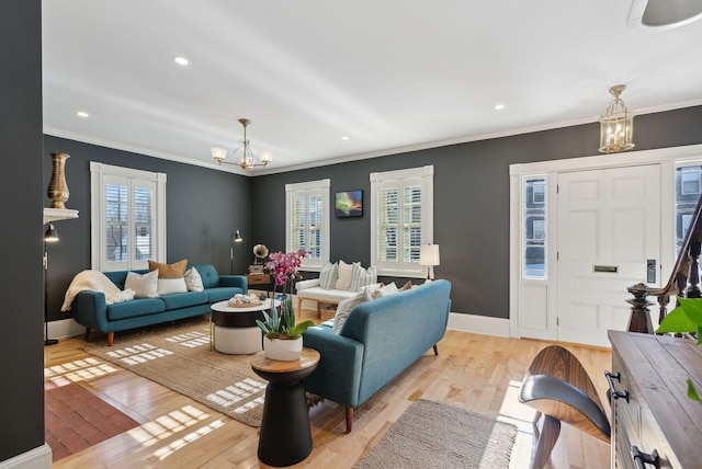 living room featuring a notable chandelier, ornamental molding, and light hardwood / wood-style floors