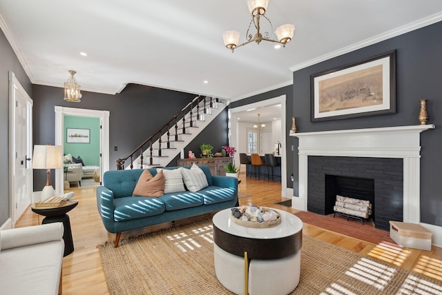 living room featuring crown molding, hardwood / wood-style floors, a notable chandelier, and a fireplace