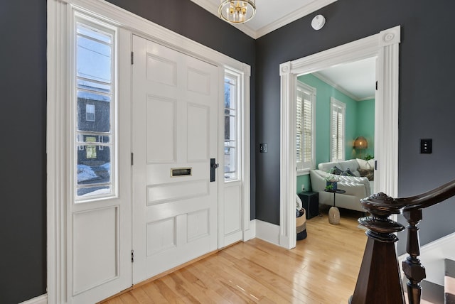 entryway with an inviting chandelier, crown molding, and light hardwood / wood-style flooring