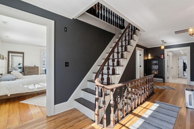 staircase with hardwood / wood-style flooring and ornamental molding