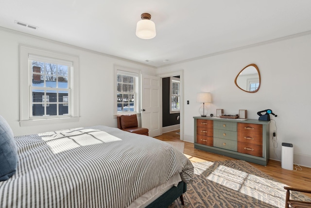 bedroom with ornamental molding and light hardwood / wood-style floors