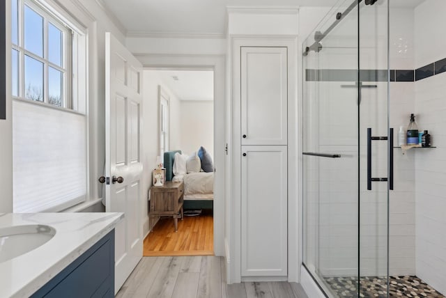 bathroom featuring ornamental molding, wood-type flooring, a shower with door, and vanity