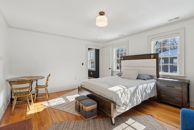 bedroom with ornamental molding and light hardwood / wood-style floors