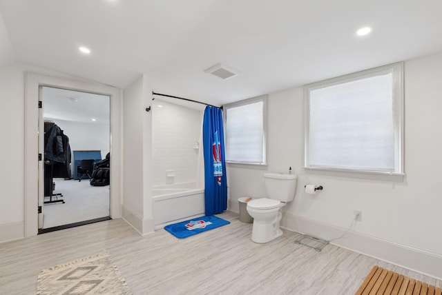 bathroom with shower / bathtub combination with curtain, hardwood / wood-style floors, and toilet