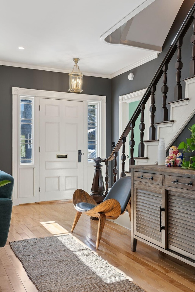 foyer entrance featuring wood-type flooring, plenty of natural light, ornamental molding, and an inviting chandelier