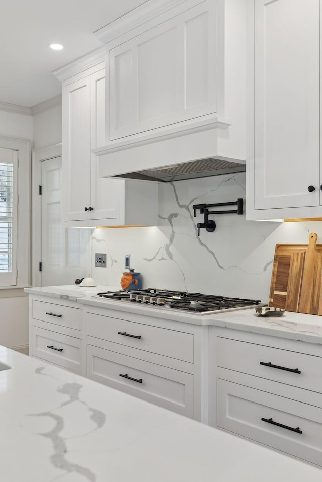 kitchen with white cabinetry, crown molding, gas cooktop, and tasteful backsplash