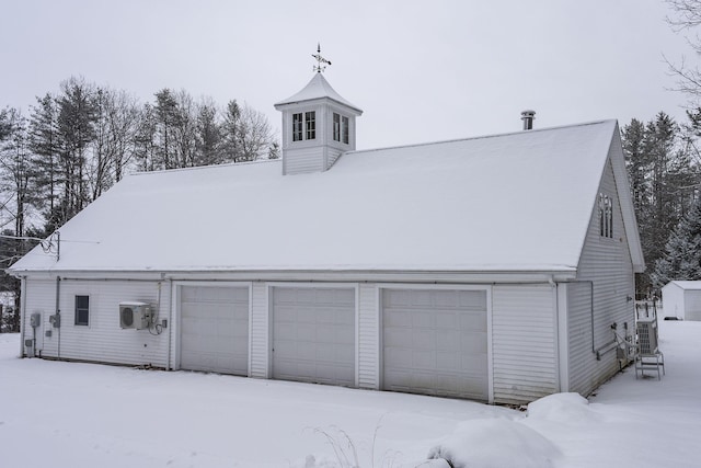 snow covered garage featuring ac unit