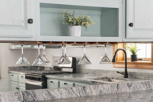 bar with white cabinetry, sink, and gas range oven