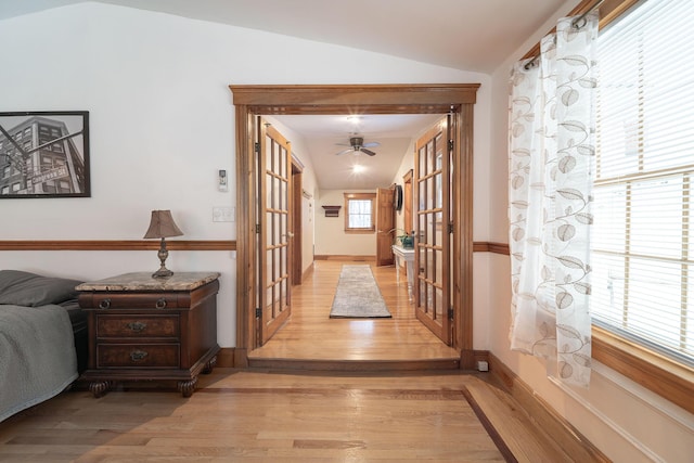 hallway featuring lofted ceiling, light wood-type flooring, and french doors