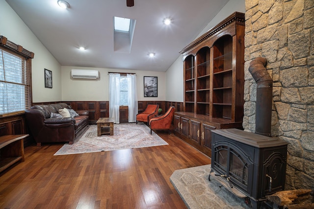 living room featuring a wall mounted air conditioner, lofted ceiling with skylight, dark hardwood / wood-style floors, and a wood stove