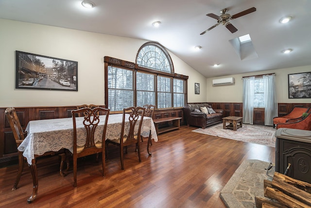 dining room with ceiling fan, a wall mounted air conditioner, lofted ceiling with skylight, and dark hardwood / wood-style flooring