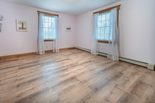 unfurnished room featuring a baseboard radiator and light hardwood / wood-style flooring