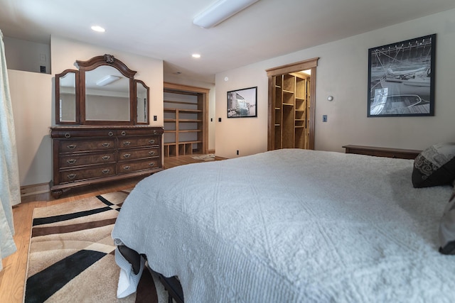 bedroom with a walk in closet and hardwood / wood-style floors