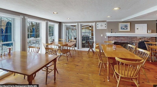 dining area featuring light hardwood / wood-style floors, a brick fireplace, and a textured ceiling