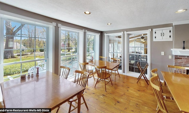 557 Coles Hill Rd, Wells, ME 04090 - dining space with a fireplace, light hardwood / wood-style floors, and a textured ceiling