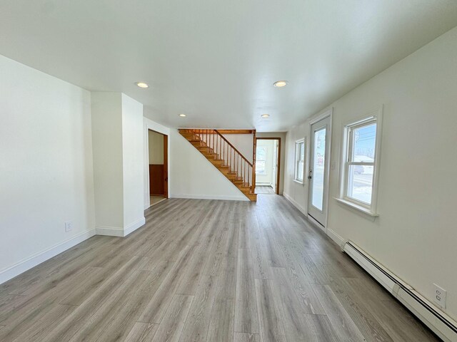 unfurnished living room featuring a baseboard radiator and light hardwood / wood-style flooring