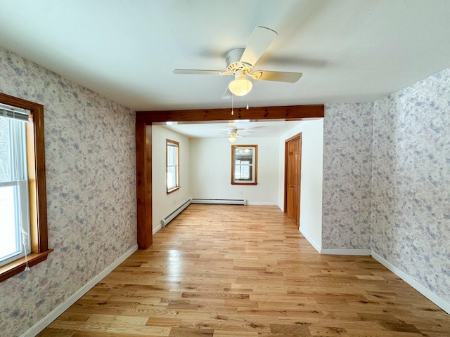 empty room featuring a baseboard heating unit and light hardwood / wood-style flooring