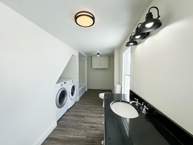 clothes washing area with dark wood-type flooring, washing machine and clothes dryer, and sink