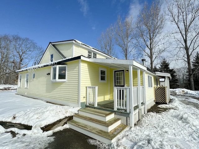 snow covered back of property with a porch