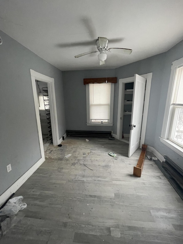 unfurnished bedroom featuring hardwood / wood-style flooring, a baseboard radiator, and ceiling fan