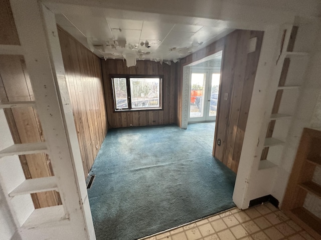 empty room with light colored carpet and wooden walls