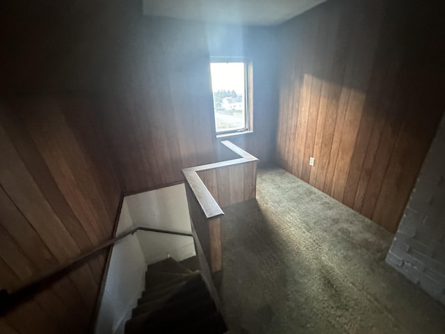 stairs with carpet flooring and wood walls