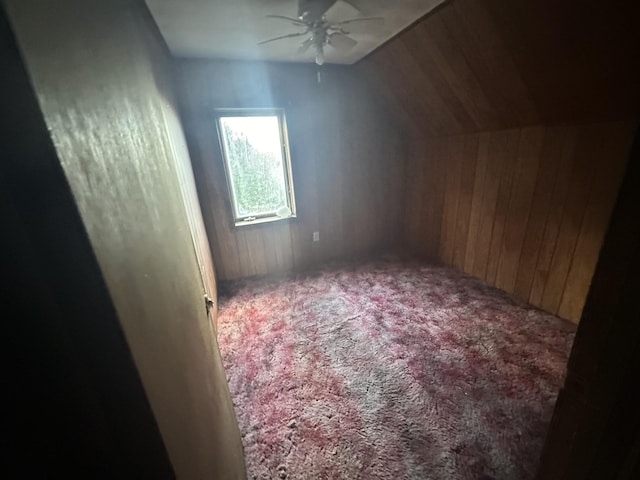 bonus room featuring ceiling fan, lofted ceiling, wooden walls, and carpet floors