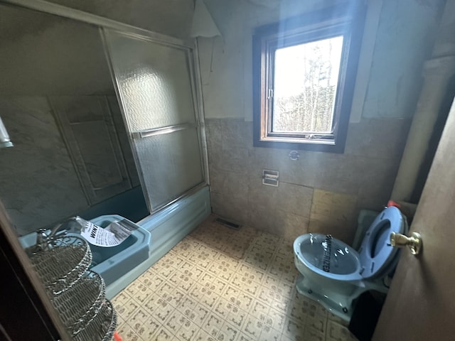 bathroom with enclosed tub / shower combo and tile walls