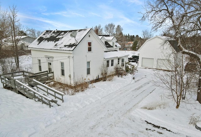 snow covered property featuring an outbuilding and a garage