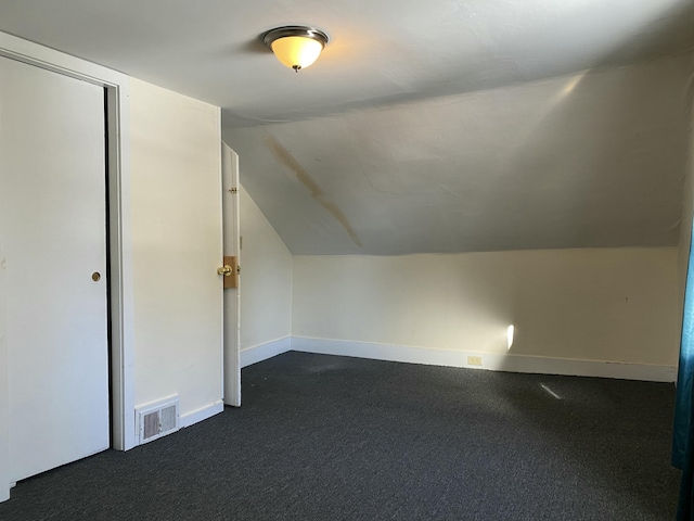 additional living space featuring lofted ceiling and dark carpet