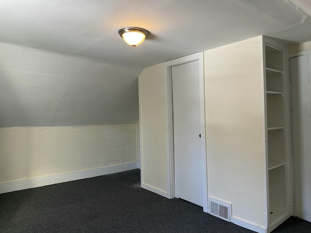 bonus room with vaulted ceiling and dark carpet