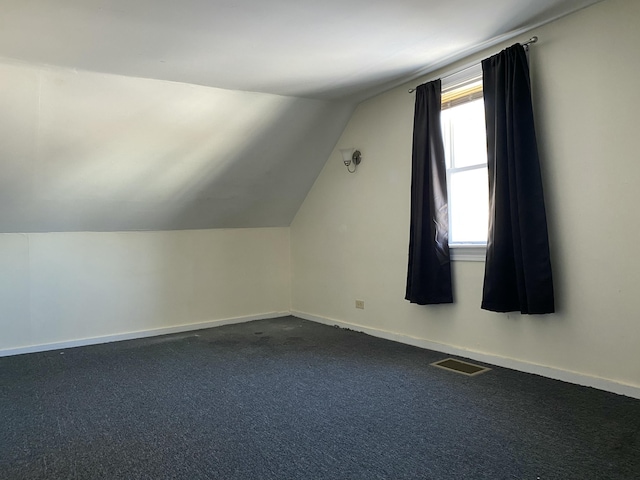 bonus room featuring vaulted ceiling and dark colored carpet