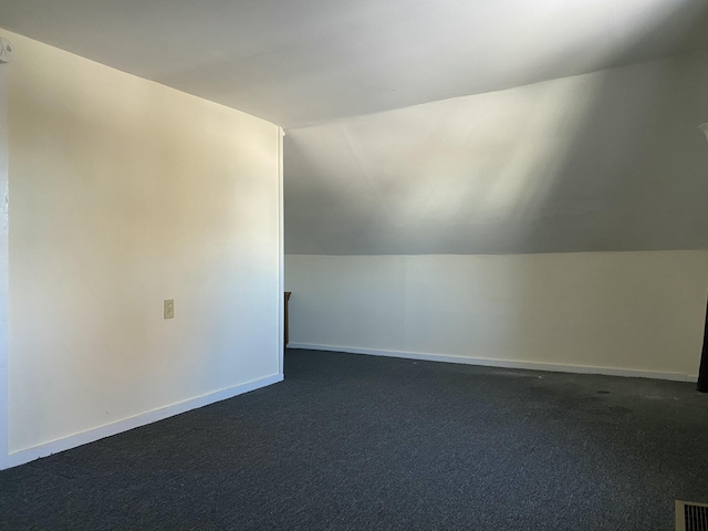 additional living space with lofted ceiling and dark carpet