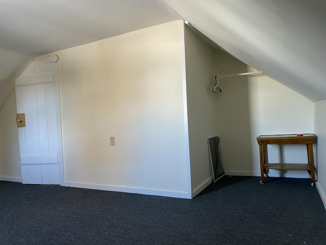 bonus room with lofted ceiling and dark carpet