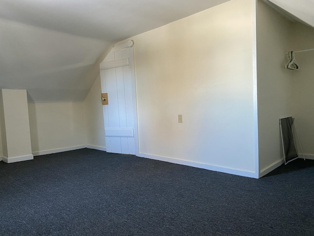 additional living space featuring lofted ceiling and dark colored carpet